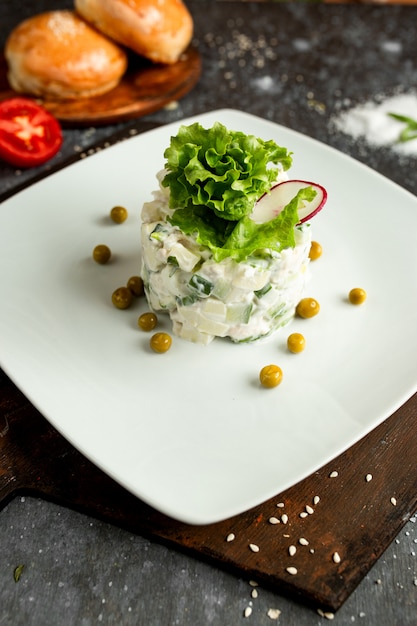 Mayonnaise salad with green peas on a white plate