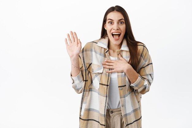 Me too Smiling excited woman raise her hand and place palm on chest introduce herself respond to offer talking about herself selfpromoting standing over white background