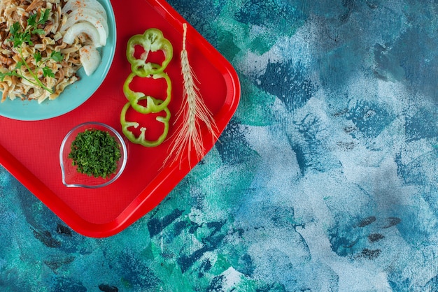 쟁반에 얇게 썬 야채가 있는 1인용 식사, 파란색 테이블 위.