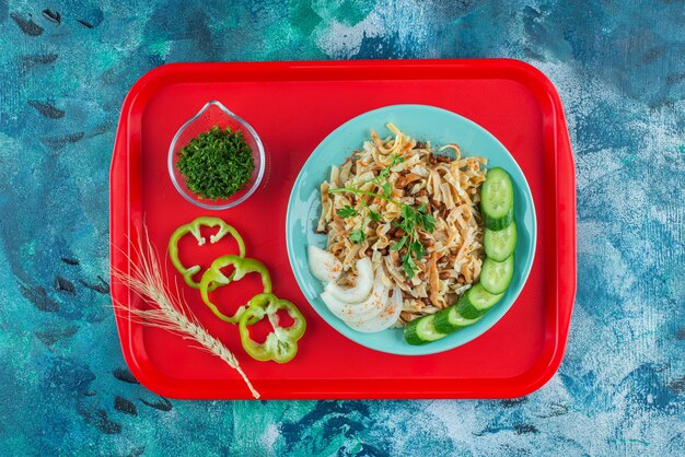 Meal for one with sliced vegetables on the tray , on the blue table. 