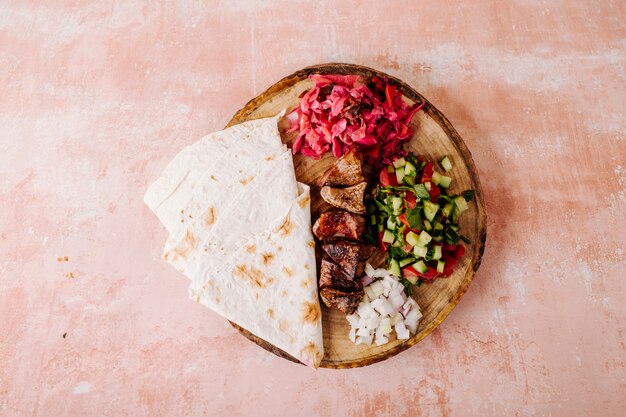 Meat barbecue with vegetable salad and lavash on a wood.