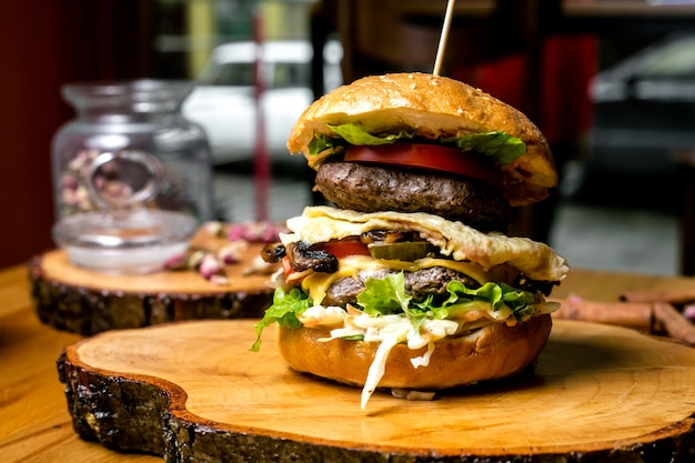 Meat burger tomato cucumber egg coleslaw lettuce cheese olives side view