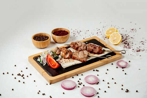 Meat pieces on a skewer with onions on a wooden board