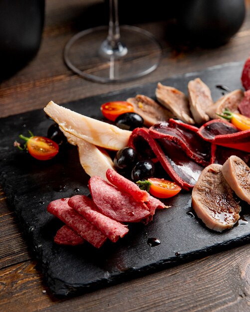 Meat plate with olives and tomatoes