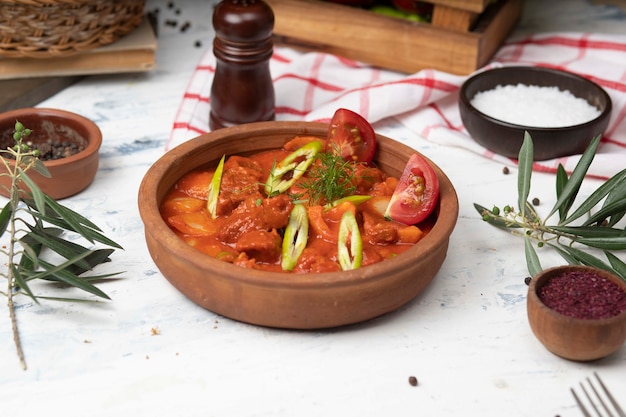 Meat potato stew with tomato sauce and pepper in pottery bowl. 
