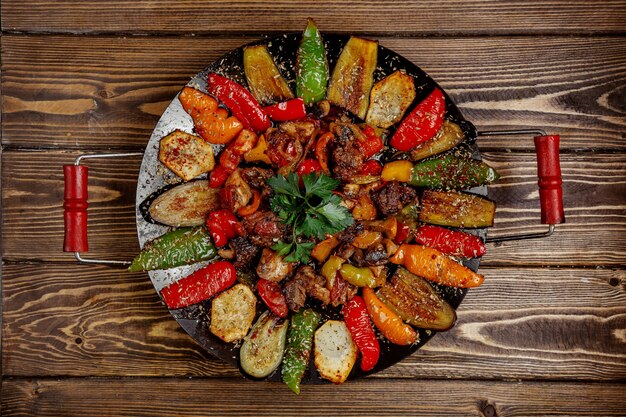 Meat sage with potatoes bell pepper and eggplant cooked on charcoal top view