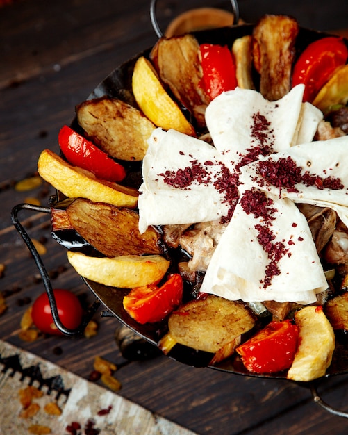 Foto gratuita saj di carne con patate melanzane e pane pita cosparsi di sumach