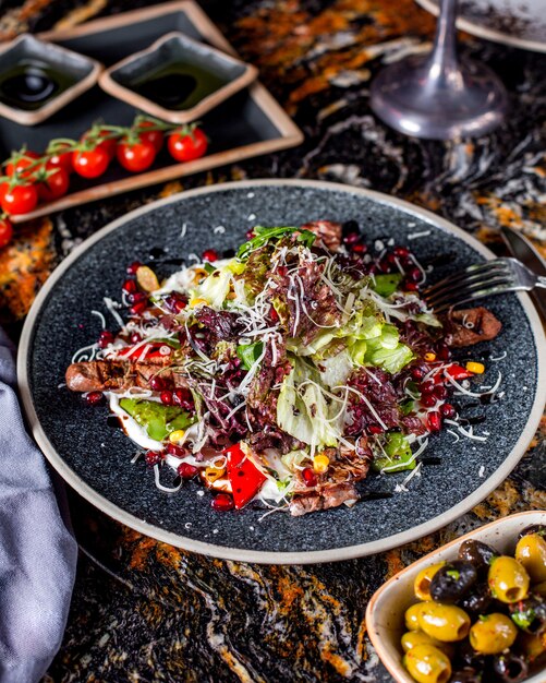 Meat salad with lettuce, corn, pomegranate and grated cheese