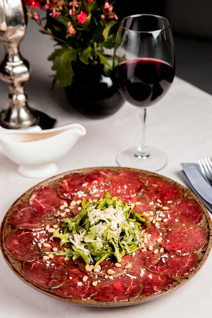 Free photo meat slices with arugula and grated cheese served with glass of wine