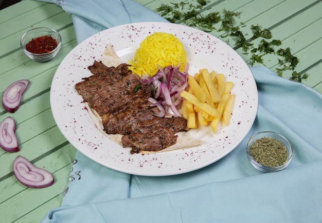 Meat steaks with fried potatoes and rice garnish