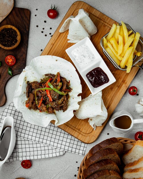 Meat stew in lavash with fries and sauces.