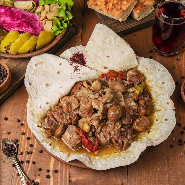 Meat stew, turshu govurma with onions, and chestnuts served in lavash. 