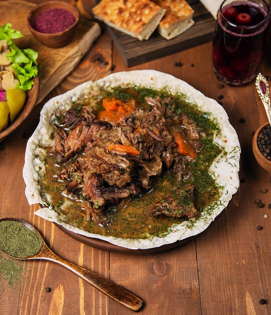Meat stew, turshu govurma with onions, green herbs, carrots in broth sauce    