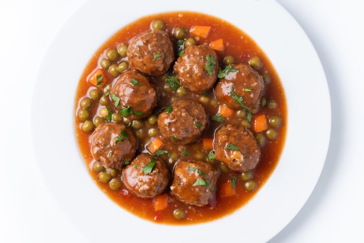 Free Photo meatballs green peas and carrot with tomato sauce isolated on white background