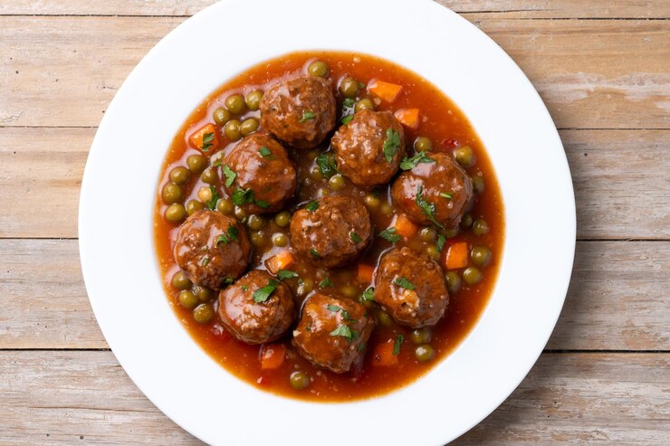 Free Photo meatballs green peas and carrot with tomato sauce on wooden table
