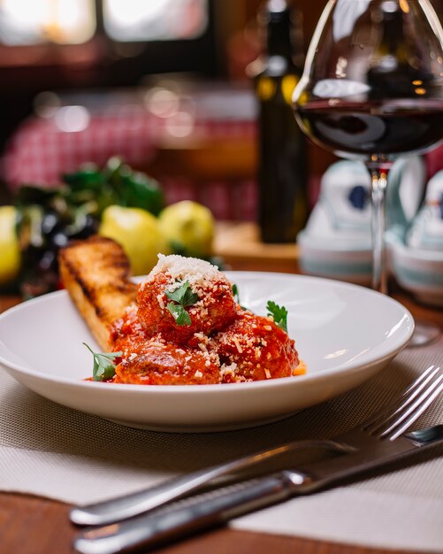 Meatballs plate garnished with tomato sauce grated parmesan and parsley