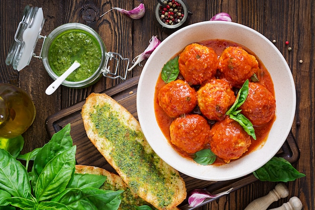 Meatballs in tomato sauce and toast with basil pesto.