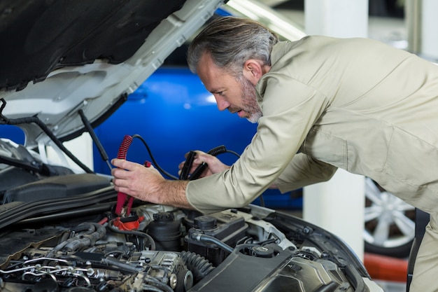 Mechanic attaching jumper cables to car battery