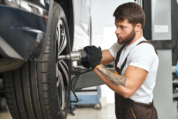 Mechanic changing wheel hubcap in automobile.