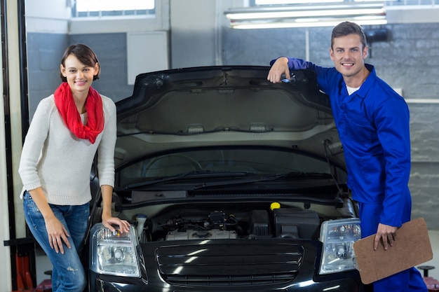 Mechanic and customer standing with car