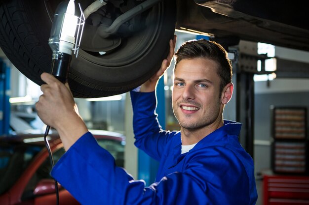 Mechanic examining car tyre using flashlight