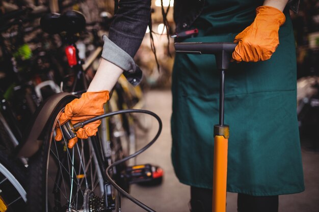 Mechanic filling air into bicycle tire with air pump