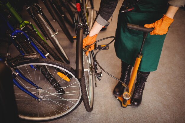 Mechanic filling air into bicycle tire with air pump