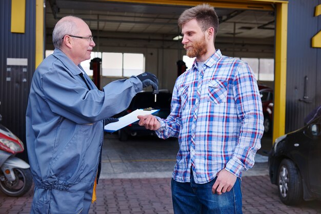 Mechanic giving the keys car to a customer