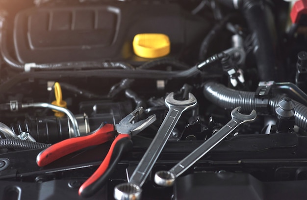 Mechanic hand checking and fixing a broken car in car service garage.