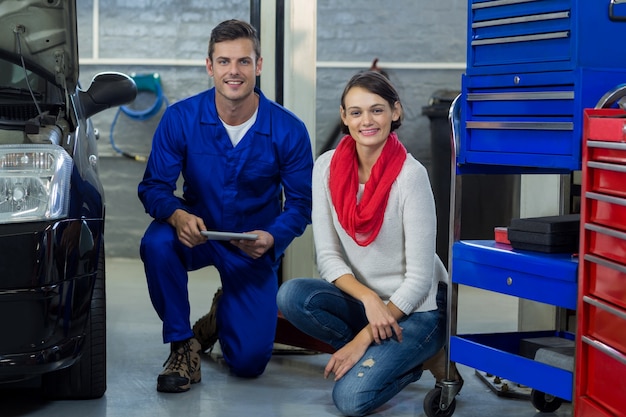 Mechanic holding digital tablet with customer