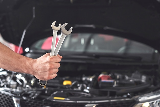 Mechanic holding pair of wrenches at the repair garage.