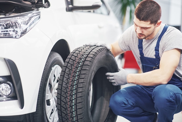 Mechanic holding a tire tire at the repair garage. replacement of winter and summer tires