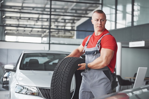 Mechanic holding a tire tire at the repair garage. replacement of winter and summer tires.