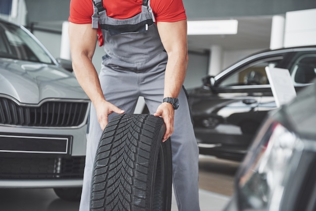 Free photo mechanic holding a tire tire at the repair garage. replacement of winter and summer tires.