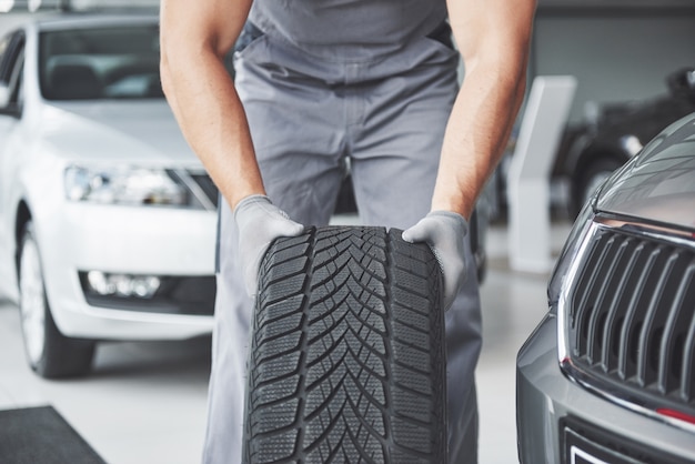 Mechanic holding a tire tire at the repair garage. replacement of winter and summer tires.