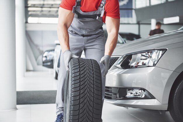 Mechanic holding a tire tire at the repair garage. replacement of winter and summer tires.