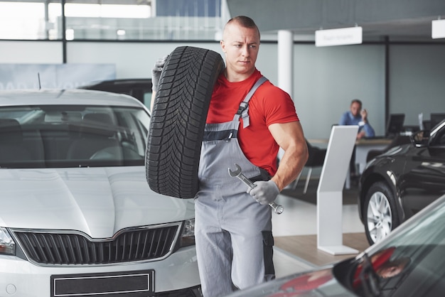 Mechanic holding a tire tire at the repair garage. replacement of winter and summer tires.