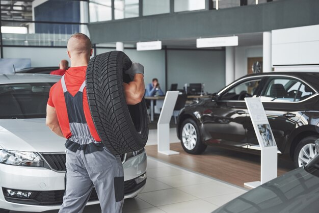 Mechanic holding a tire tire at the repair garage. replacement of winter and summer tires.