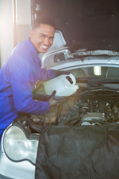 Foto gratuita meccanico versando olio lubrificante nel motore auto