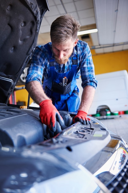 Foto gratuita meccanico che ripara un'auto in officina