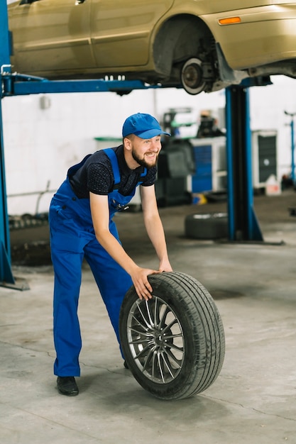 Free photo mechanic rolling wheel to car elevator