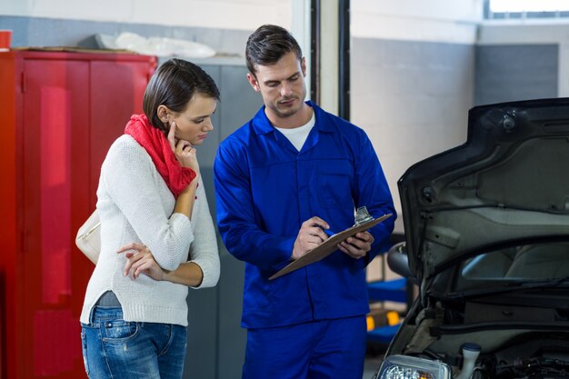 Mechanic showing check list to customer