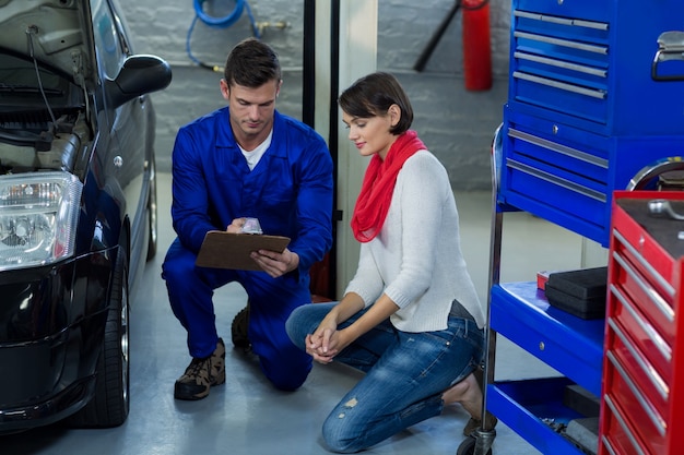 Mechanic showing check list to customer