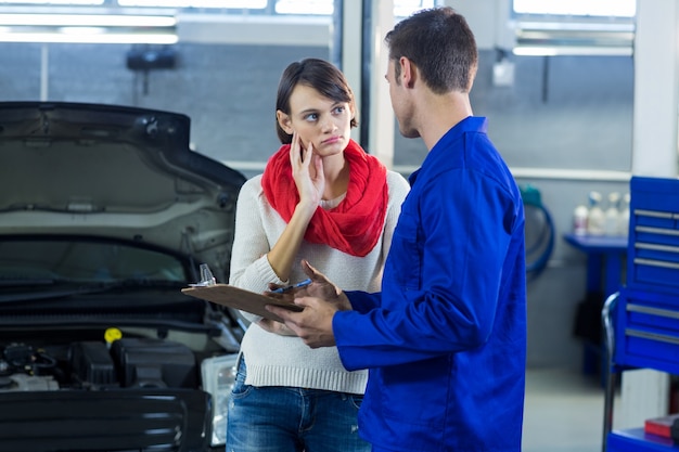 Mechanic showing check list to customer