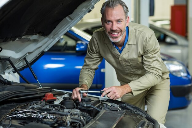 メカニック車のエンジンにサービスを提供しながら、笑顔