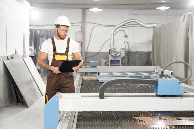 Mechanic standing near cnc and controlling cutting of plasma