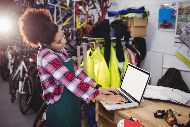 Mechanic talking on mobile phone while using laptop