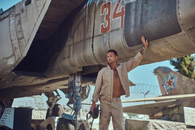 Mechanic in uniform standing near a war fighter-interceptor in an open-air museum.