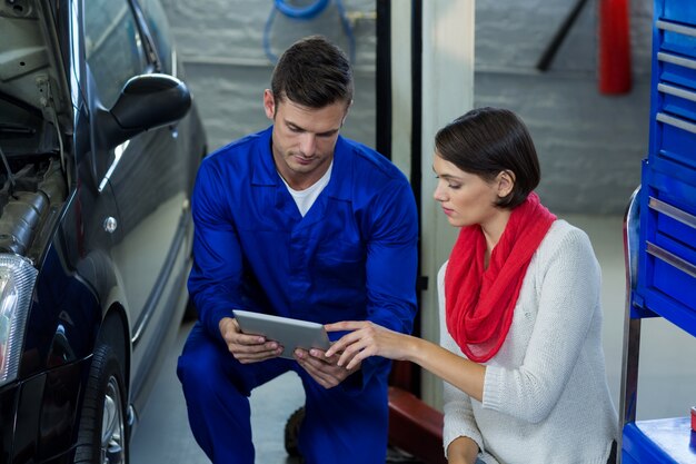 Mechanic using digital tablet with customer