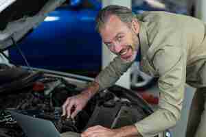 Free photo mechanic using laptop while servicing car engine